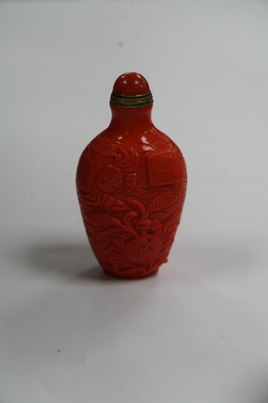 A Chinese coral coloured glass 'crabs' snuff bottle, 8.2cm high. Condition - good